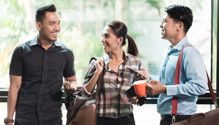 Three happy colleagues at work talking and laughing