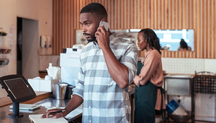 A cafe owner checking bills and contacting his bank
