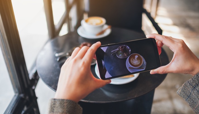 Woman taking a photo of her coffee and food