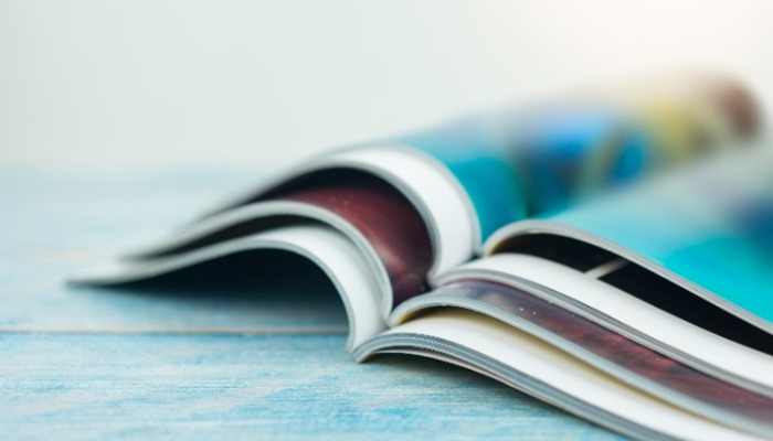 Magazines stacked on top of each other with blurry print ads